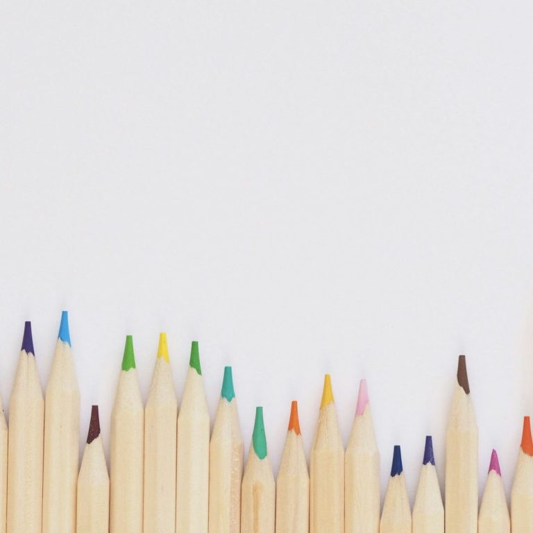 Colored pencils arranged in a row against a white background.