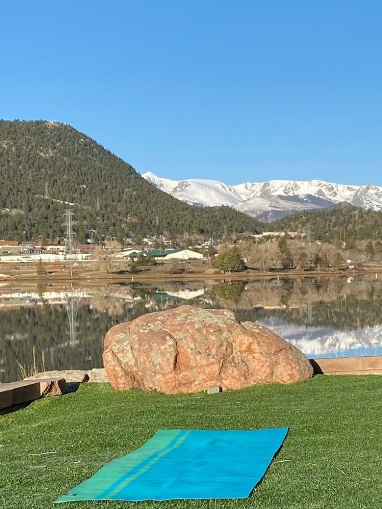 Estes Park Yoga Yoga Mat in front of Estes Park Lake with Rocky Mountains in the background and reflected in the lake